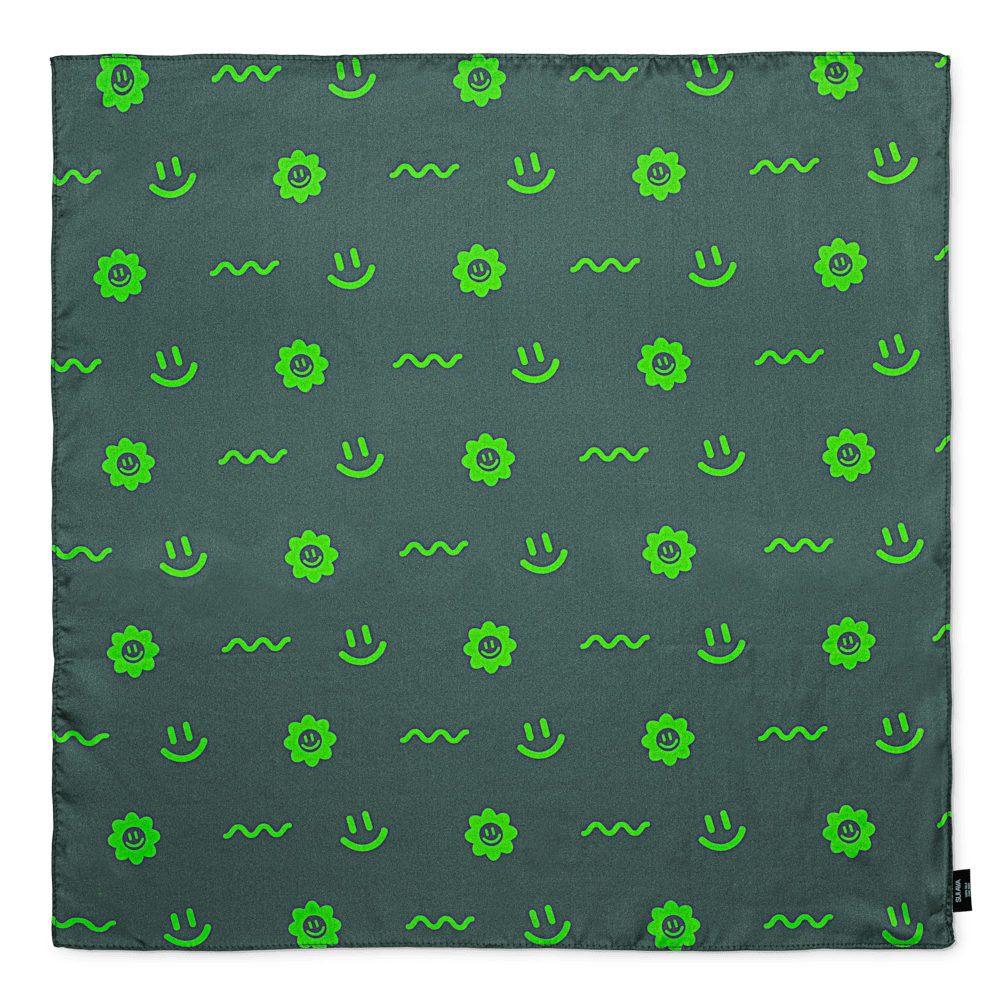 Silketørklæde i mørkegrøn med mønster af limegrønne smileys, blomster og bølger.