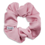 Rosa scrunchie med blødt satinlook og SUI AVA-logo, formet i let bølgende struktur.