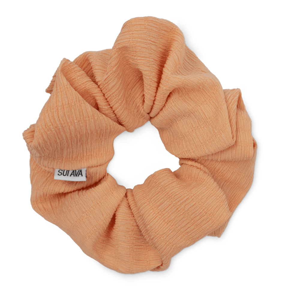 Ea Zig-Zag Scrunchie i orange er en blød og elastisk scrunchie i en varm, energisk nuance. Perfekt til en skånsom frisure eller som et dekorativt armbånd.