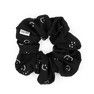 Ea Smile Often Scrunchie – sort hårelastik med hvide smiley-ansigter og ribstruktur